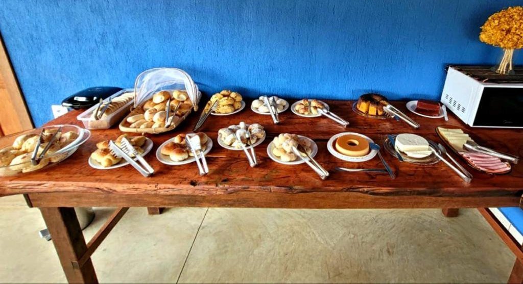 Mesa de café da manhã em madeira com pães, bolos, queijos e frios